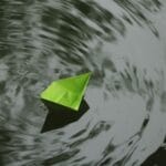 Zielona papierowa łódka origami płynie po pofalowanej wodzie