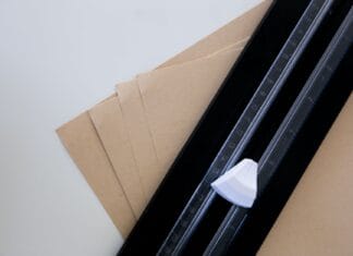 Kostka introligatorska z kości, plastiku czy teflonu? Porównanie do pracy z papierem Brązowe arkusze papieru z linijką i nożykiem introligatorskim