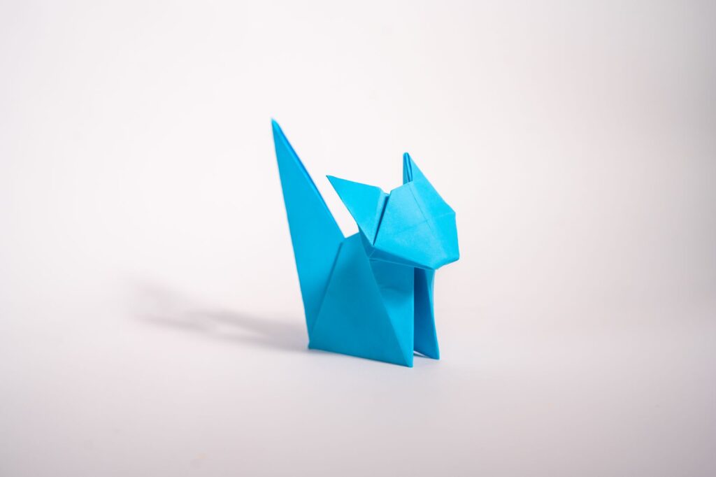 Niebieski kot origami na białym tle