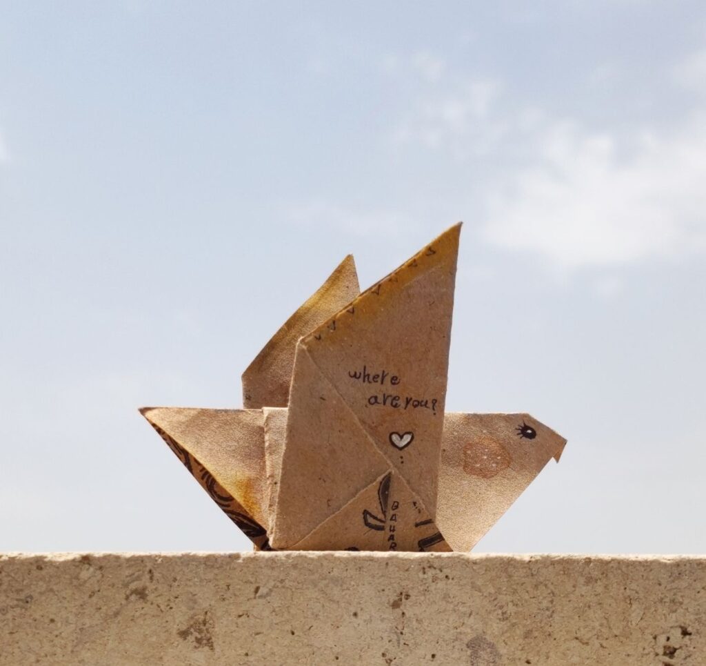 Papierowy ptak origami na krawędzi z napisem Where are you? na tle nieba